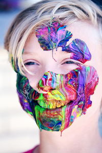 Close-up of smiling boy with colorful paints on face