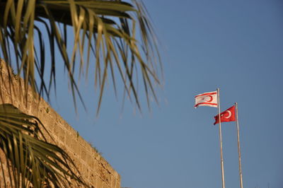 Low angle view of flags against clear blue sky