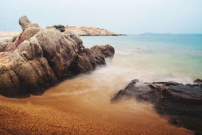 Scenic view of rocks on shore against sky