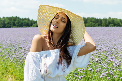 Woman in sun hat standing on field against sky