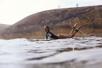 Happy woman sitting on surfboard in sea