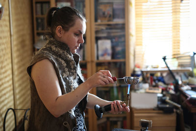 The master woman near the bench works with tools, on the torch boils water with a metal plate. 