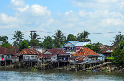 Houses by lake and buildings against sky