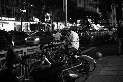Man sitting on bicycle at sidewalk in city during night