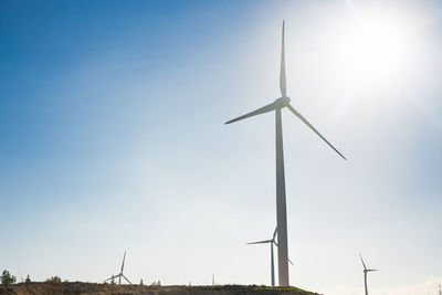 Low angle view of wind turbines against sky