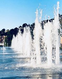 Water splashing in swimming pool against clear blue sky