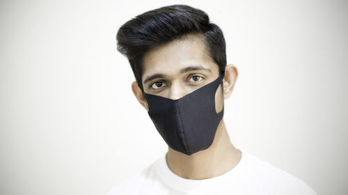 Portrait of man covering face against white background