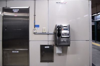 Pay phone mounted on wall at subway station