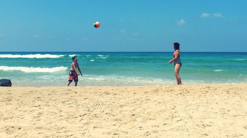 Mother playing volleyball with son at beach