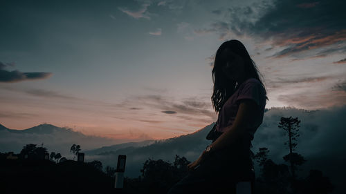 Silhouette woman looking at sunset