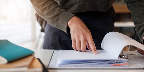 Midsection of man reading book on table