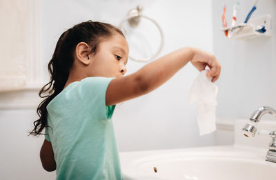 Cute girl washing napkin at sink