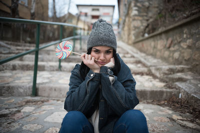 Portrait of young woman having lollipop while sitting on steps