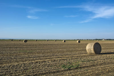 Hay bales on field against sky