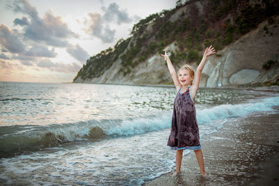 Full length of boy standing at beach against sky