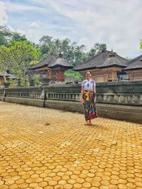 Full length of young woman standing against built structure