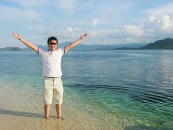 Young man standing on beach against sky