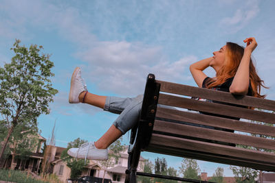 Low angle view of woman sitting against sky