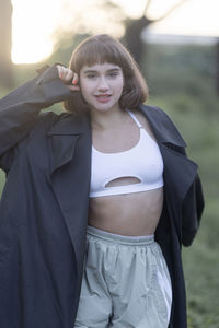 Portrait of young woman standing against trees