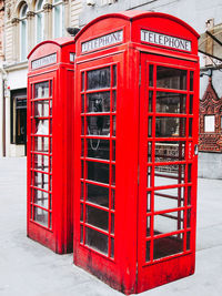 Red telephone booth on sidewalk in city