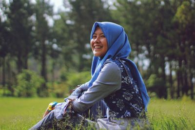 Portrait of smiling young woman sitting on field