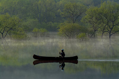 Man in boat on lake against trees