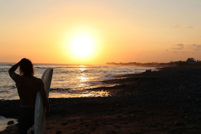 Rear view of woman on beach during sunset