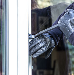 Cropped hands of burglar opening window