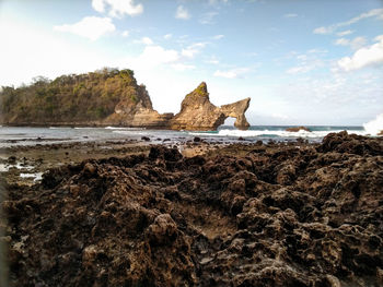 Rock formation on beach against sky