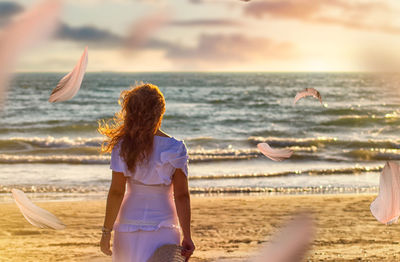 Rear view of women at beach against sky