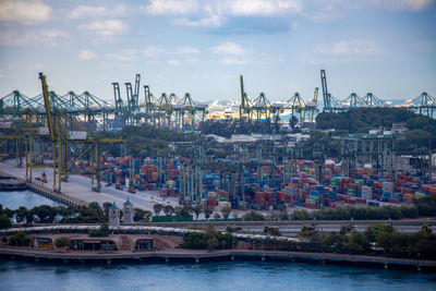 Cranes at harbor against sky in city