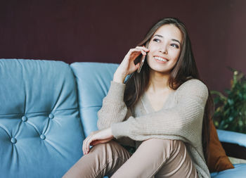 Portrait of a smiling young woman sitting on sofa