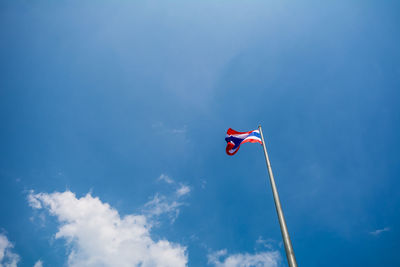 Low angle view of thai flag waving against blue sky
