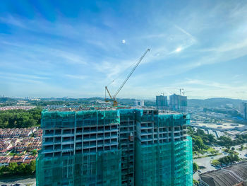 Aerial view of crane and buildings against blue sky