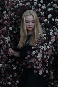 Portrait of a beautiful young woman standing by flowering plants