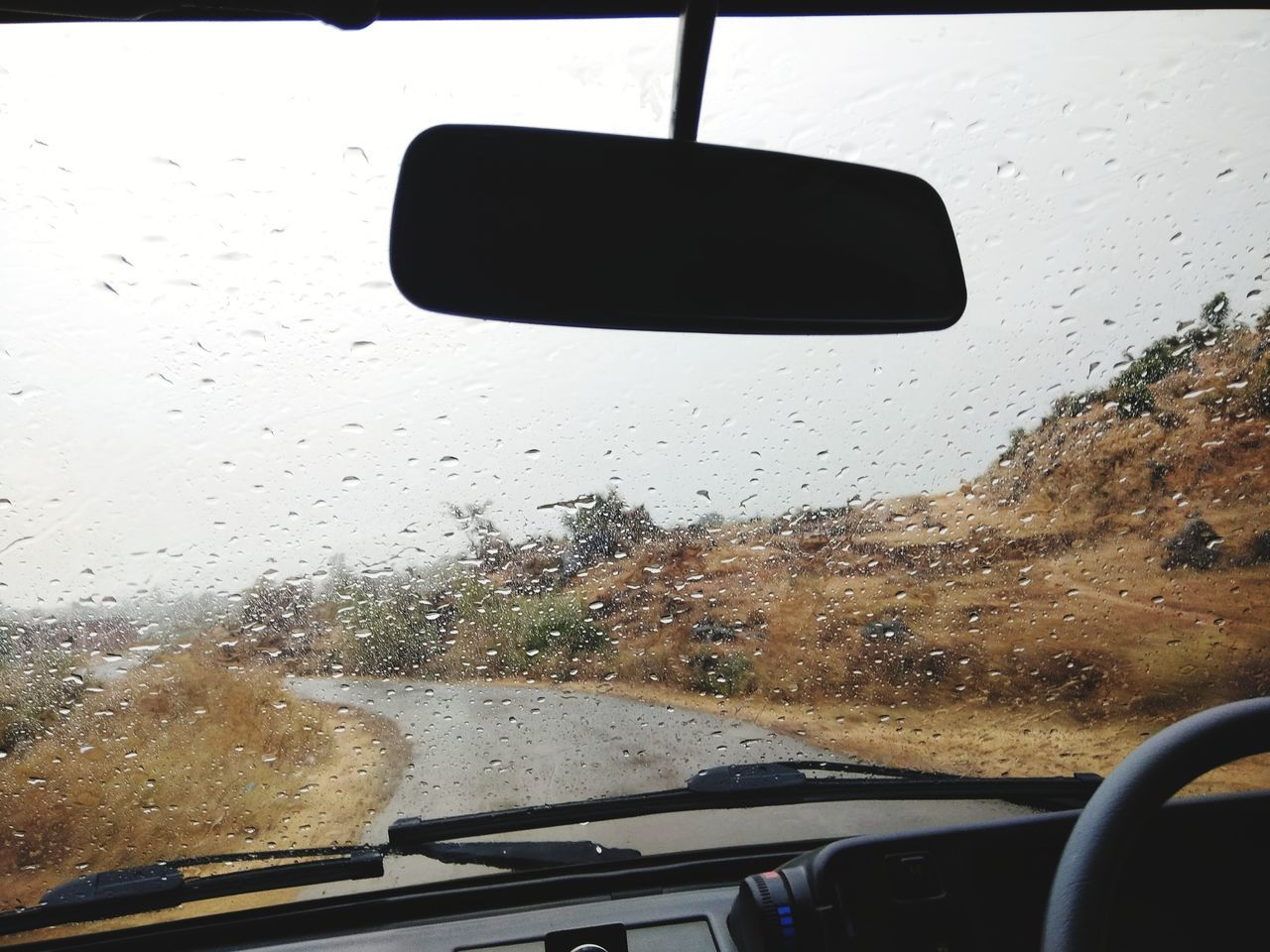 CAR ON ROAD SEEN THROUGH WET GLASS WINDOW