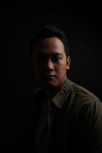 Portrait of young man against black background