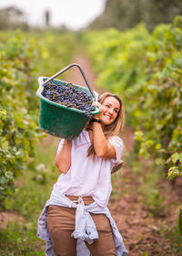 Portrait of smiling young woman holding blueberries in basket