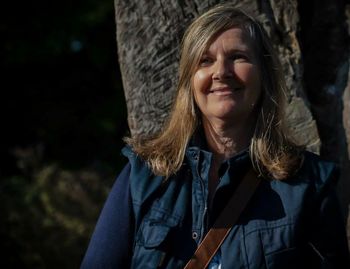 Portrait of a smiling young woman against tree trunk