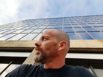 Low angle view of mature man against modern glass building in city