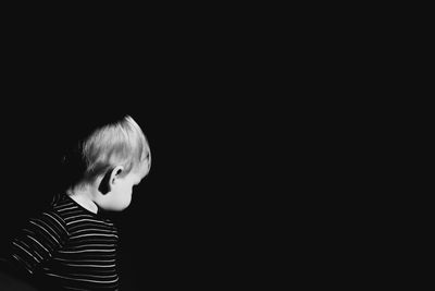 Close-up of boy against black background