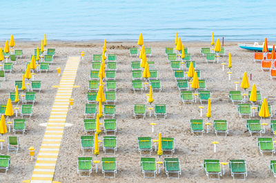 Beach lounge area with yellow umbrellas and green sunbeds on italian coastline.