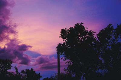 Low angle view of silhouette trees against dramatic sky