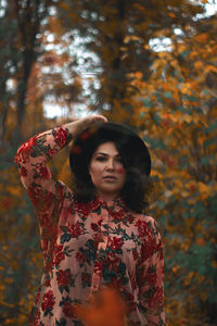 Portrait of beautiful woman standing by tree during autumn