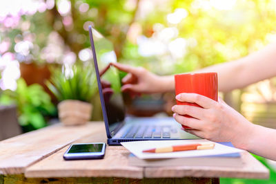 Midsection of man using mobile phone on table