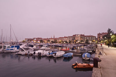 Boats moored at harbor in sea against sky