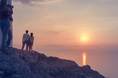 Rear view of couple standing on rock against sea