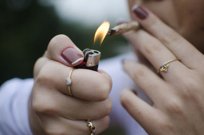 Close-up of woman holding cigarette lighter and marijuana joint