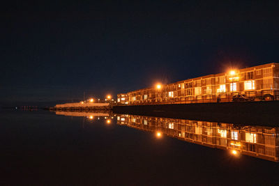 Illuminated bridge over river at night