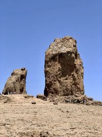 Low angle view of rock formations against clear blue sky